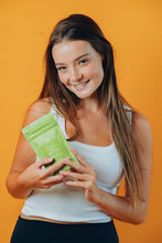 Load image into Gallery viewer, Model holding Terra Vida Matcha Clay Salt Exfoliant for Face and Body
